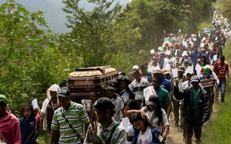 Comunidades campesinas e indígenas cargando el ataúd de un líder social asesinado en zona montañosa