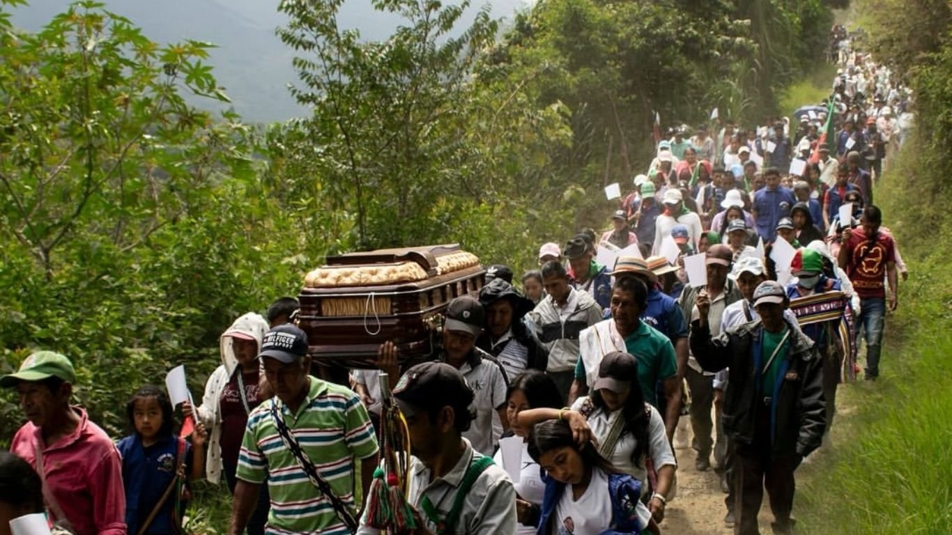 Comunidades campesinas e indígenas cargando el ataúd de un líder social asesinado en zona montañosa